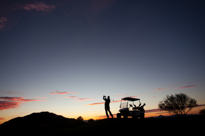 Male Caucasian Golfer Swinging A Golf Club with Cart 